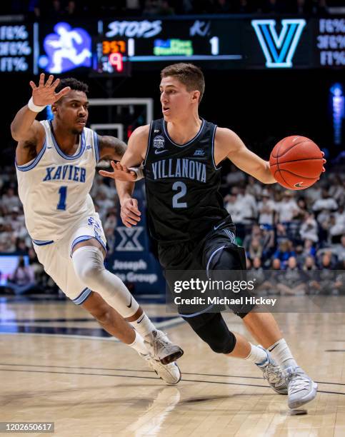 As Paul Scruggs of the Xavier Musketeers defends Collin Gillespie of the Villanova Wildcats drives to the basket during the first half at Cintas...