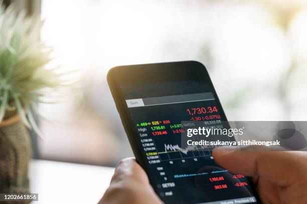 businessman trading stocks with smarthphone and check stock market data - devolución del saque fotografías e imágenes de stock