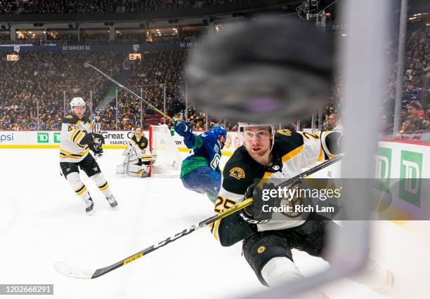 Brandon Carlo of the Boston Bruins chases after the puck after Tyler Motte of the Vancouver Canucks cleared the puck off the glass during NHL action...