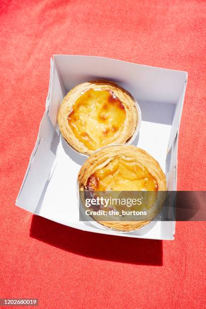 pastel de natas in a box on red tablecloth, typical portuguese tarts - pastel de nata stock pictures, royalty-free photos & images