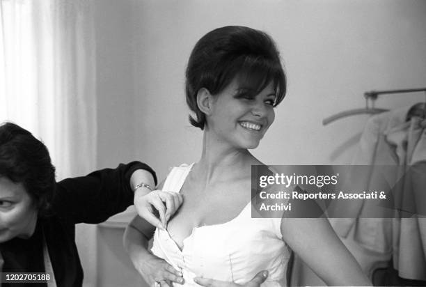 Seamstress adjusting the dress worn by Italian actress Claudia Cardinale at Nina Ricci's fashion house in Paris. Paris, 10th February 1962