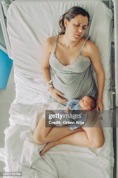 mère fatiguée dormant avec son bébé - baby close up bed photos et images de collection