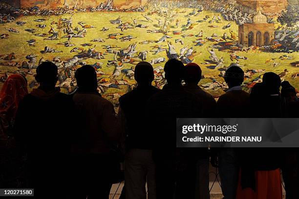 Indian visitors look at a painting depicting the Amritsar Massare at Jallianwala Bagh in Amritsar on February 4, 2010. The Amritsar Massacre, also...