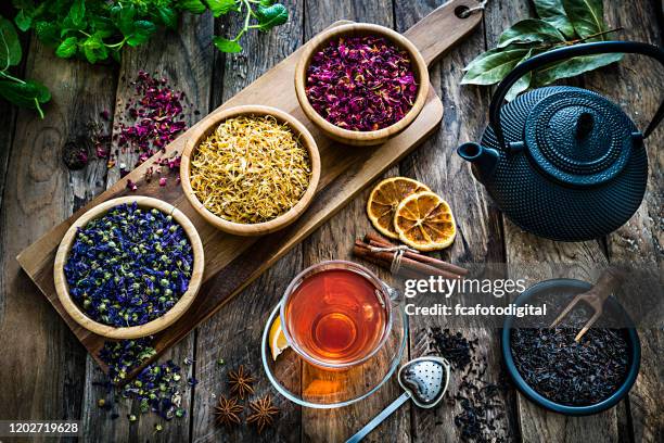 ハーブティー:様々な乾燥した茶葉と素朴な木製のテーブルの上から撮影された花とティーカップ - dried tea leaves ストックフォトと画像