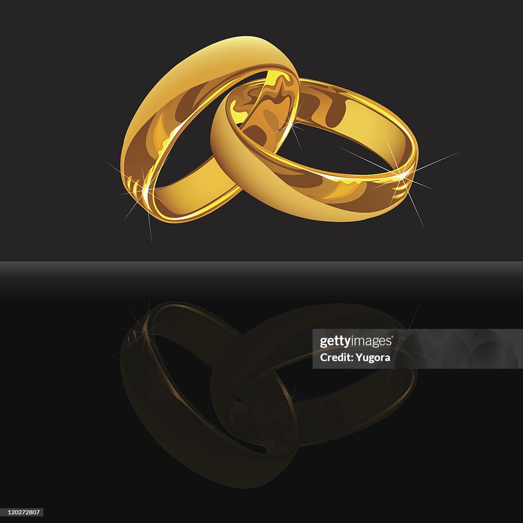 Gold wedding rings on black background with reflection