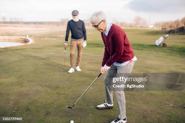 senior woman taking a golf shot - friends studio shot stock pictures, royalty-free photos & images