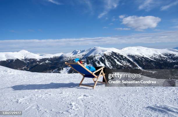 woman sitting in a chair in snow, enjoying the winter sun, après-ski lounge at the top of  turracher höhe, austria. - neige épaisse photos et images de collection