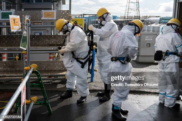 Workers wear protective suits at Tokyo Electric Power Co.'s Fukushima Dai-ichi nuclear power plant on January 29, 2020 in Okuma, Fukushima...