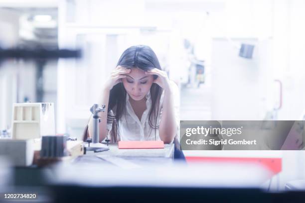 asian woman in deep thought in technical office - bata de laboratório - fotografias e filmes do acervo