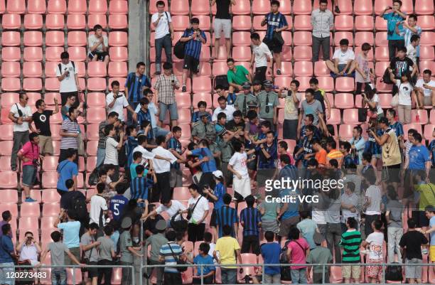 An AC Milan fan, with red jersey, is surrounded by Inter Milan fans during an Inter Milan training session at Beijing Workers Stadium on August 2,...