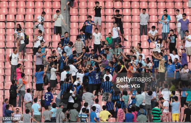 An AC Milan fan, with red jersey, is surrounded by Inter Milan fans during an Inter Milan training session at Beijing Workers Stadium on August 2,...