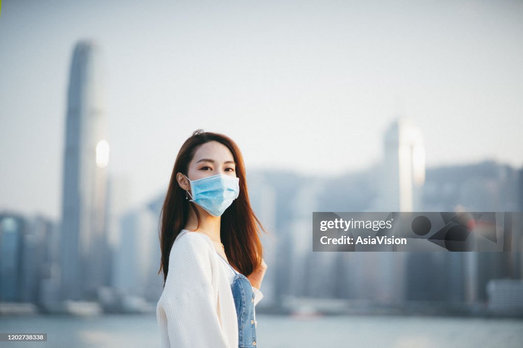 発生をめぐる世界的な健康緊急事態であるコロナウイルスの拡散を防ぐために保護フェイスマスクを着用した若いアジア人女性