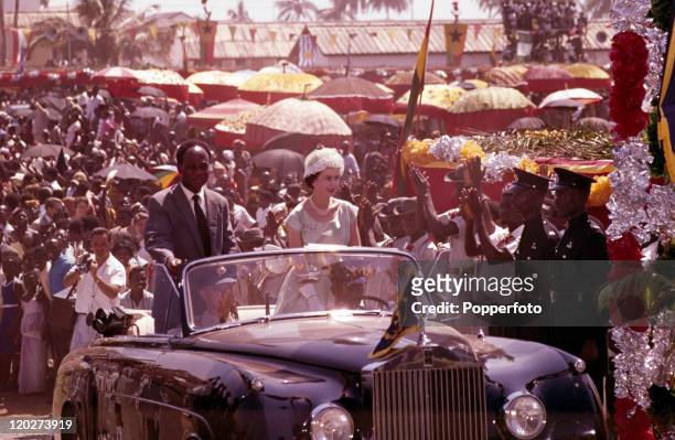 Queen Elizabeth II and President Kwame Nkrumah of Ghana ride in an open-top limousine through cheering crowds in Accra, Ghana during the Royal Tour...