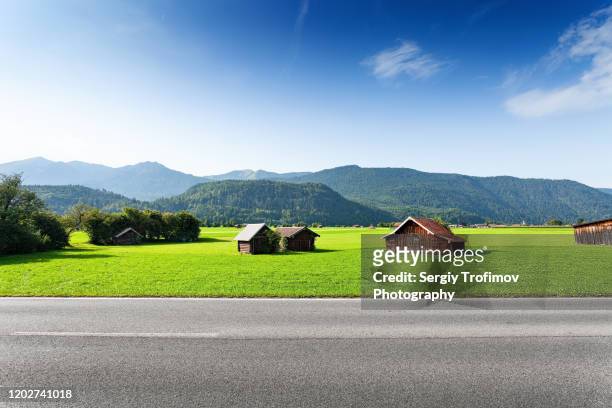 bavarian landscape with huts along the road, side view - horizontal stock-fotos und bilder
