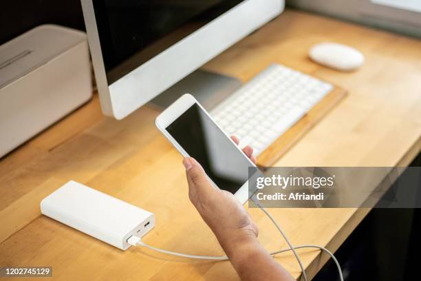 close-up of smart device connected to a portable charger - power bank imagens e fotografias de stock