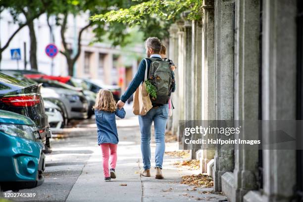 rear view of father with small girls walking outdoors on the sidewalk in city. - slovakia stock pictures, royalty-free photos & images