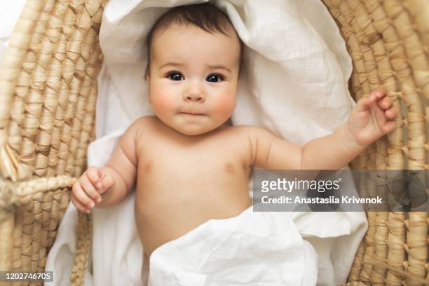 adorable smiling beautiful baby girl lying in vintage baby wicker cot. - innocence fotografías e imágenes de stock