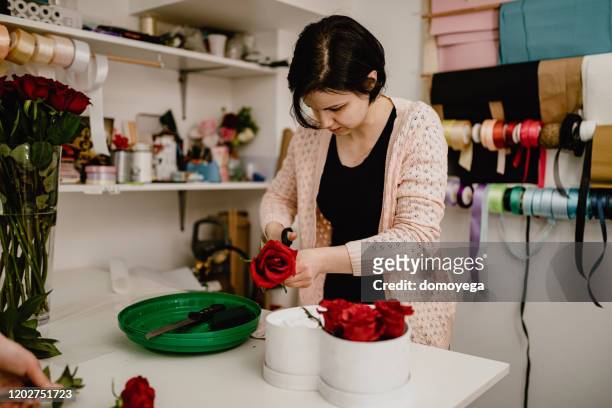 vrouw die bloemdoosregeling met rode rozen maakt - dozen roses stockfoto's en -beelden