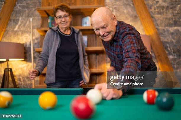 gelukkige actieve oudsten die van poolspel tijdens de wintervakanties in hotel genieten - billiard ball game stockfoto's en -beelden