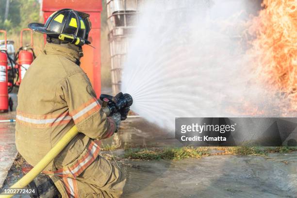 fireman operating a water fire hose. - spray nozzle stock pictures, royalty-free photos & images