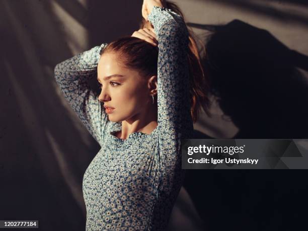 young redhead woman tying hair - pferdeschwanz stock-fotos und bilder