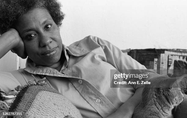 Portrait of American artist and educator Mildred Thompson as she poses with her cat, Asterix, on a couch in her studio, Washington DC, May 30, 1979.