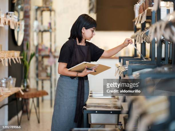Young latin woman working in organic store and checking products