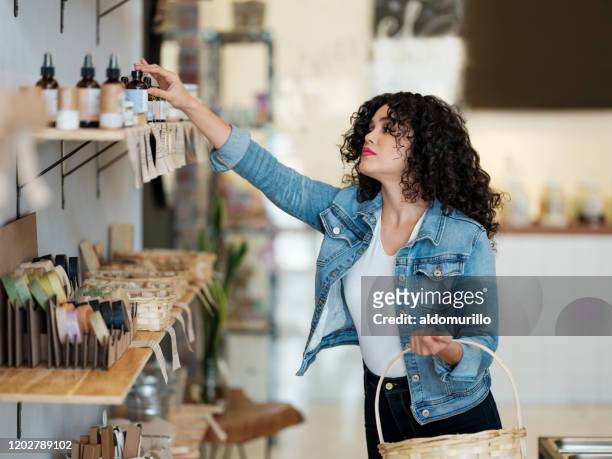 belle jeune femme faisant des emplettes avec le panier dans le magasin zéro de déchet - magasin cosmétique photos et images de collection