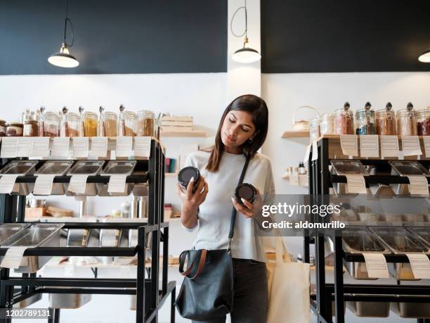 mujer joven sosteniendo tarros en almacén de residuos cero - concept store fotografías e imágenes de stock