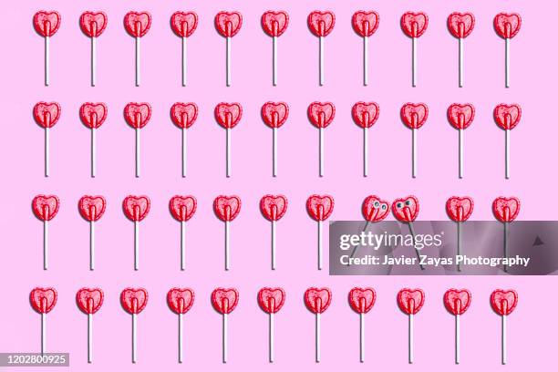 many red heart lollipops in pink background - lolly stockfoto's en -beelden