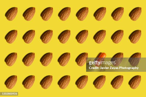 many almonds arranged on yellow background and one capsule - almond milk stock pictures, royalty-free photos & images