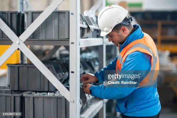 warehouse male worker examining goods in factory - building shelves stock pictures, royalty-free photos & images