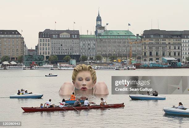 People in boats approach "Die Badende" , a giant sculpture showing a woman's head and knees as if she were resting in the Binnenalster lake on August...