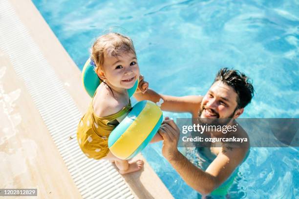 linda niña divirtiéndose con los padres en la piscina - niño bañandose fotografías e imágenes de stock