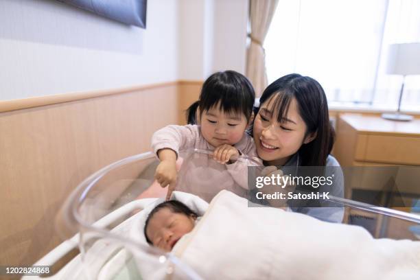 madre e figlia piccola guardano il neonato in ospedale - lettino ospedale foto e immagini stock