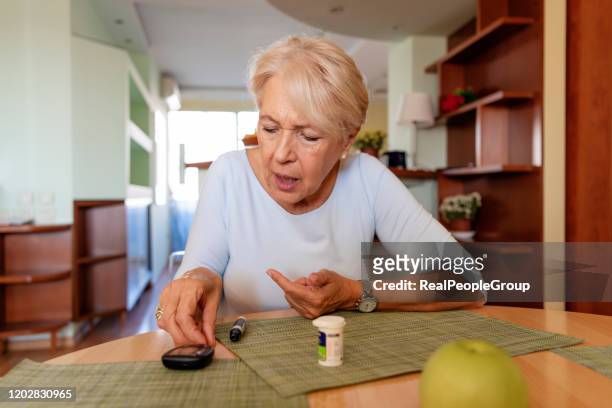 mujer mayor con gluctorio para controlar el azúcar en la sangre - glycemia fotografías e imágenes de stock