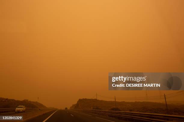 Cars drive on the TF-1 highway during a sandstorm in Santa Cruz de Tenerife, on the Canary Island of Tenerife, on February 23, 2020. - Airports on...