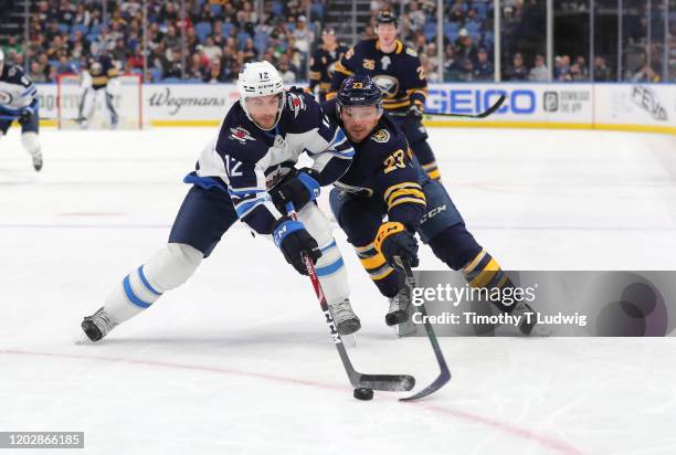 Dylan DeMelo of the Winnipeg Jets and Sam Reinhart of the Buffalo Sabres go after a loose puck during the second period at KeyBank Center on February...