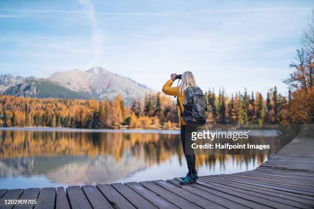 a senior woman hiker in autumn nature, using binoculars. - tatra mountains photos et images de collection