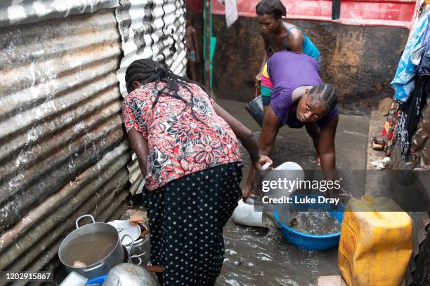 Residents clear flood water from outside their shacks inside the Povoado slum on January 29, 2020 in Luanda, Angola. In June 2013, 3000 families were...