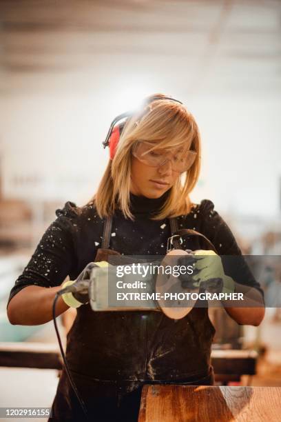 een timmermanvrouw die het document van een orbitale schuurmachine verandert terwijl het werken in een winkel - replacement stockfoto's en -beelden