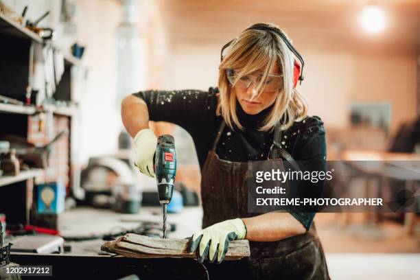 een timmermanvrouw die het document van een orbitale schuurmachine verandert terwijl het werken in een winkel - drill stockfoto's en -beelden