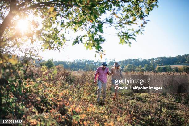 young couple outdoors on a walk in autumn nature. - young couple enjoying a walk through grassland stock pictures, royalty-free photos & images
