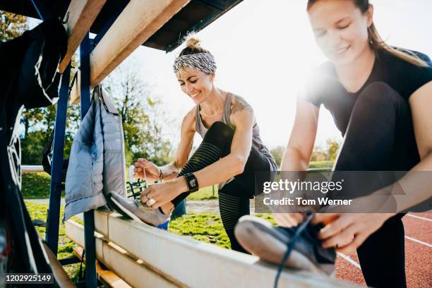 two friends tying shoelaces before going for run together - schnürsenkel stock-fotos und bilder