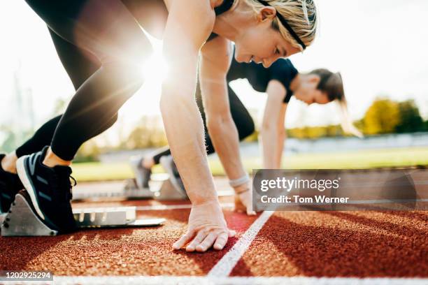 close up of women at starting blocks on outdoor track - womens track stock pictures, royalty-free photos & images