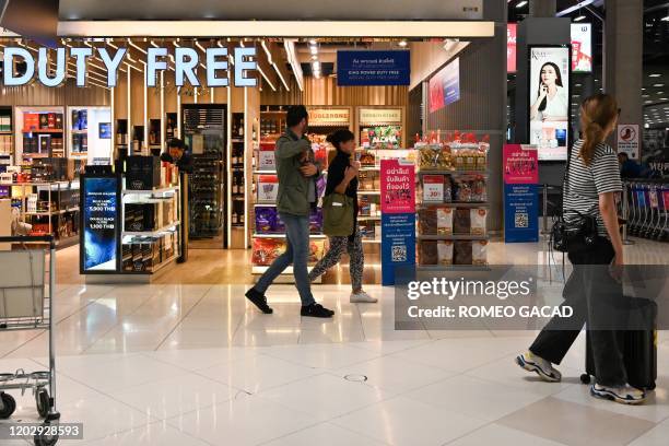 This photo taken on February 23, 2020 shows passengers walking past a duty free shop at the arrival area of Suvarnabhumi Airport in Bangkok.