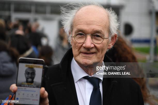 John Shipton, father of WikiLeaks founder Julian Assange, holds up a smartphone playing paying a video of supprt for his son as he arrives at...