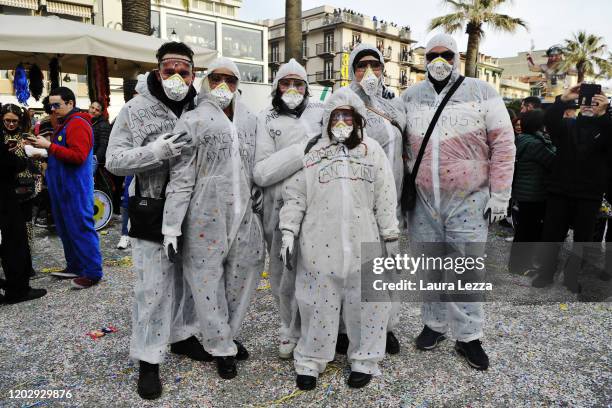 Group of participants in the Carnival of Viareggio wear a carnival mask that reads 'Carnevale Antivirus' and a protective mask against the...