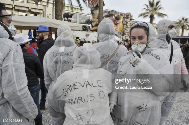 Group of participants in the Carnival of Viareggio wear a carnival mask that reads 'Carnevale Antivirus' and a protective mask against the...