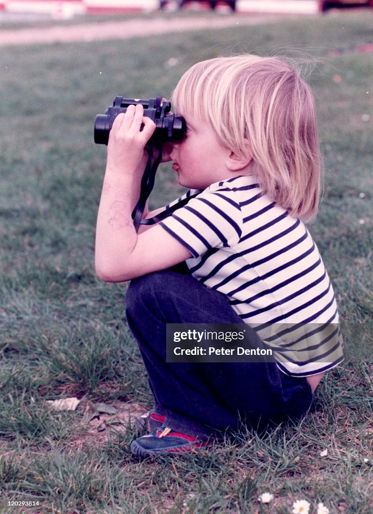 Boy siiting on heel and looking from binocular